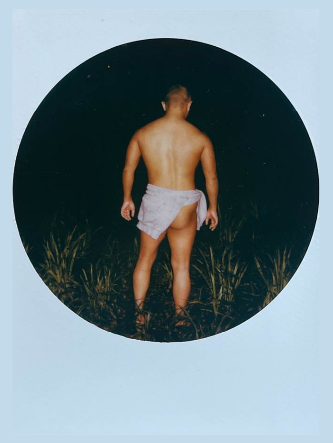 圆形画面中站在草丛里的男子背影